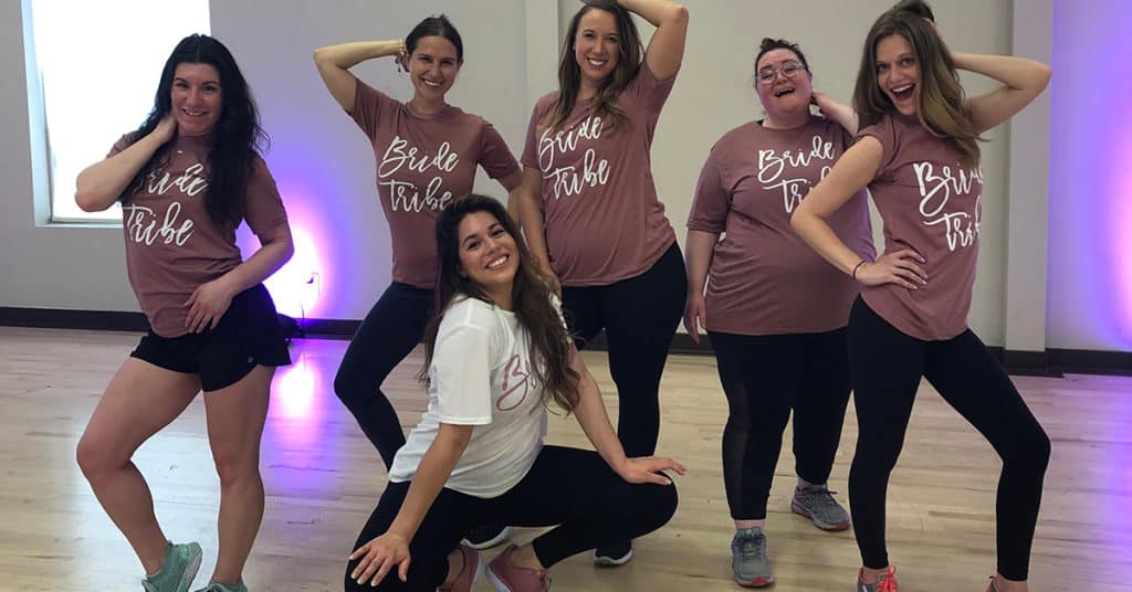 Six Women Posing in Bride Tribe T-shirts After a DivaDance Bachelorette Party