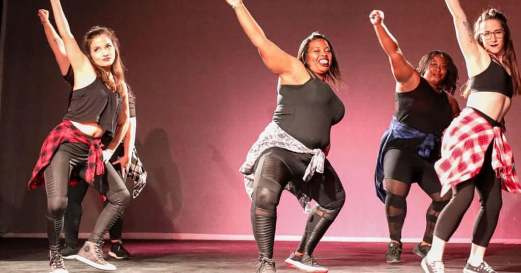 Five Diverse Women Dancing and Raising Their Right Fists in the Air