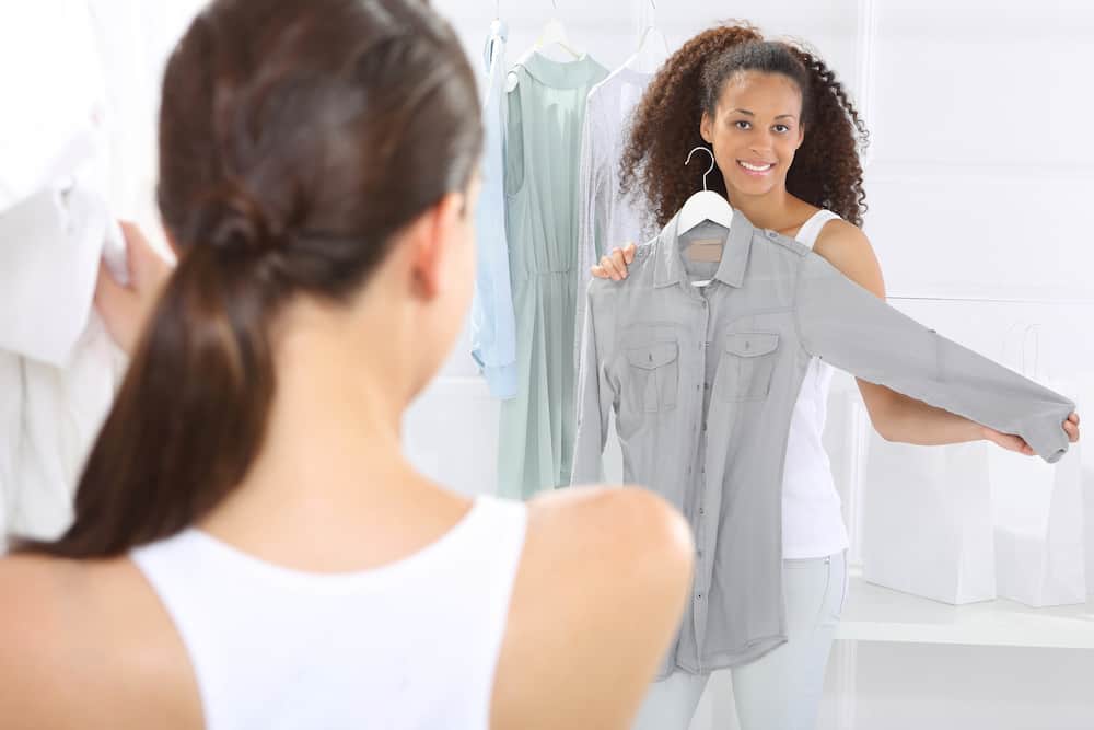 A woman looking at a shirt in a boutique.