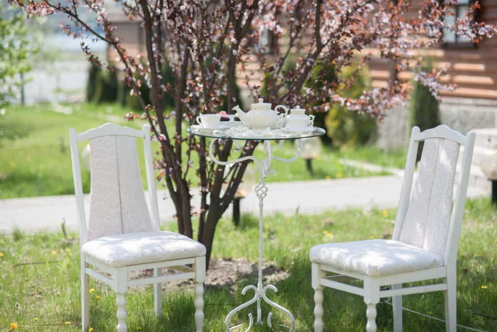 Two white chairs and a table are set up in the grass, perfect for enjoying a relaxing afternoon in Sugar Land.