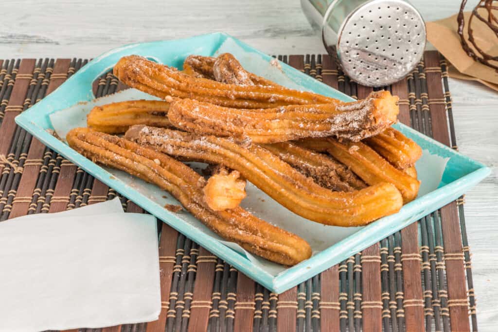 A plate of churros on a wooden table.