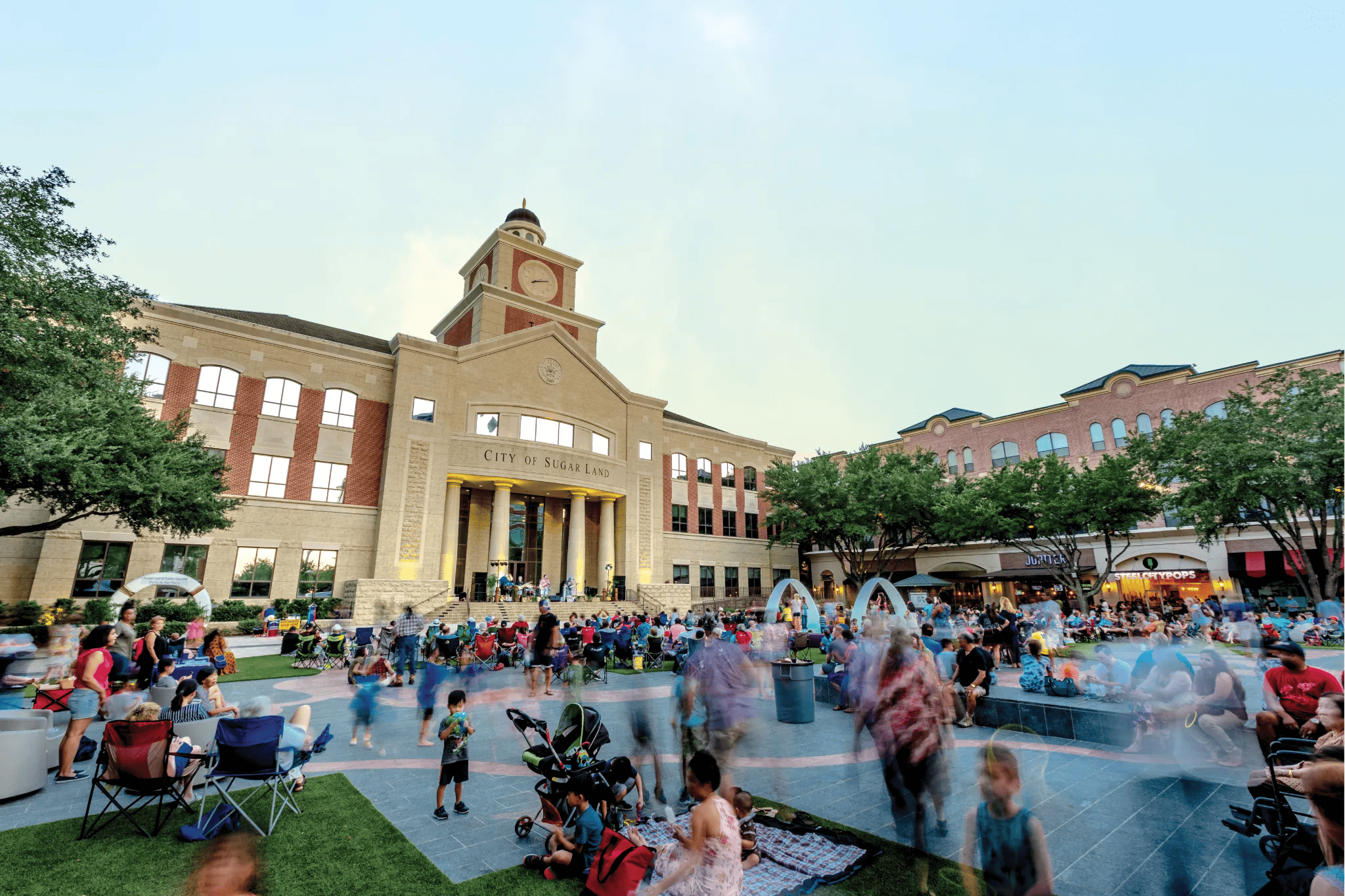 Looking for things to do in Sugar Land? Check out the crowd gathered in front of a building with a clock tower.