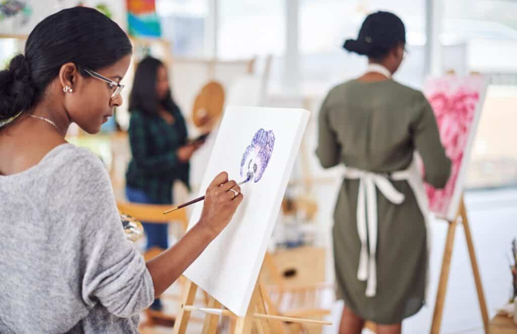 Woman painting on a canvas in an art class.