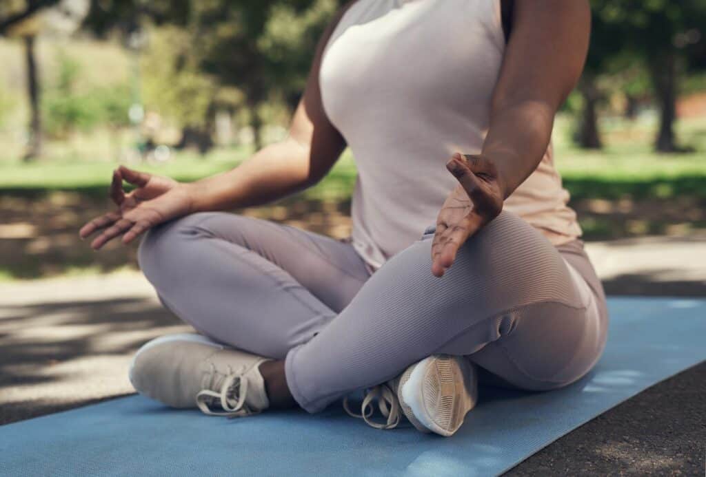 Woman practicing yoga in a seated meditation pose outdoors.