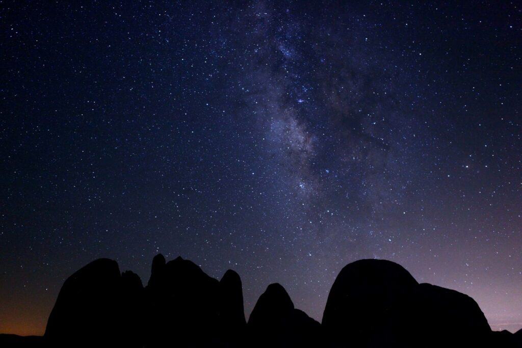 Silhouetted mountains against a starry night sky with the milky way visible.