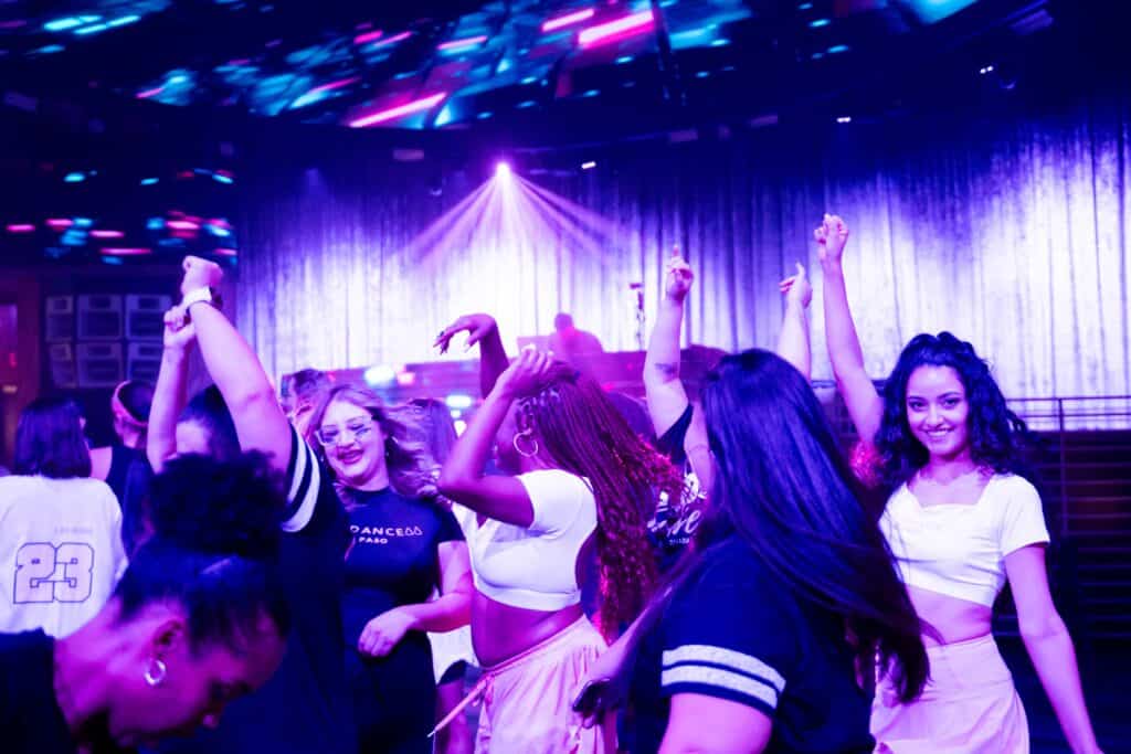 Group of people dancing and enjoying themselves under vibrant club lights.