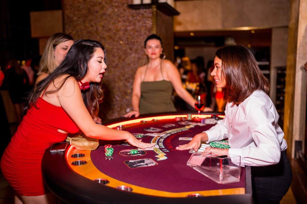 Women engaging in a card game at a casino table.