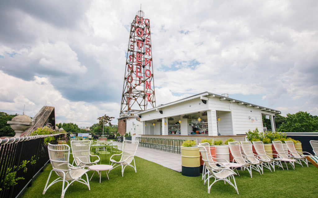 Rooftop venue in Sandy Springs with seating area, ideal for a bachelorette, and a large, iconic neon sign in the background under a cloudy sky.