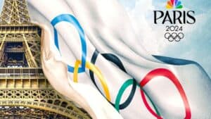Image of the Eiffel Tower with the Olympic rings and Paris 2024 logo, partially covered by a flag displaying the Olympic rings.